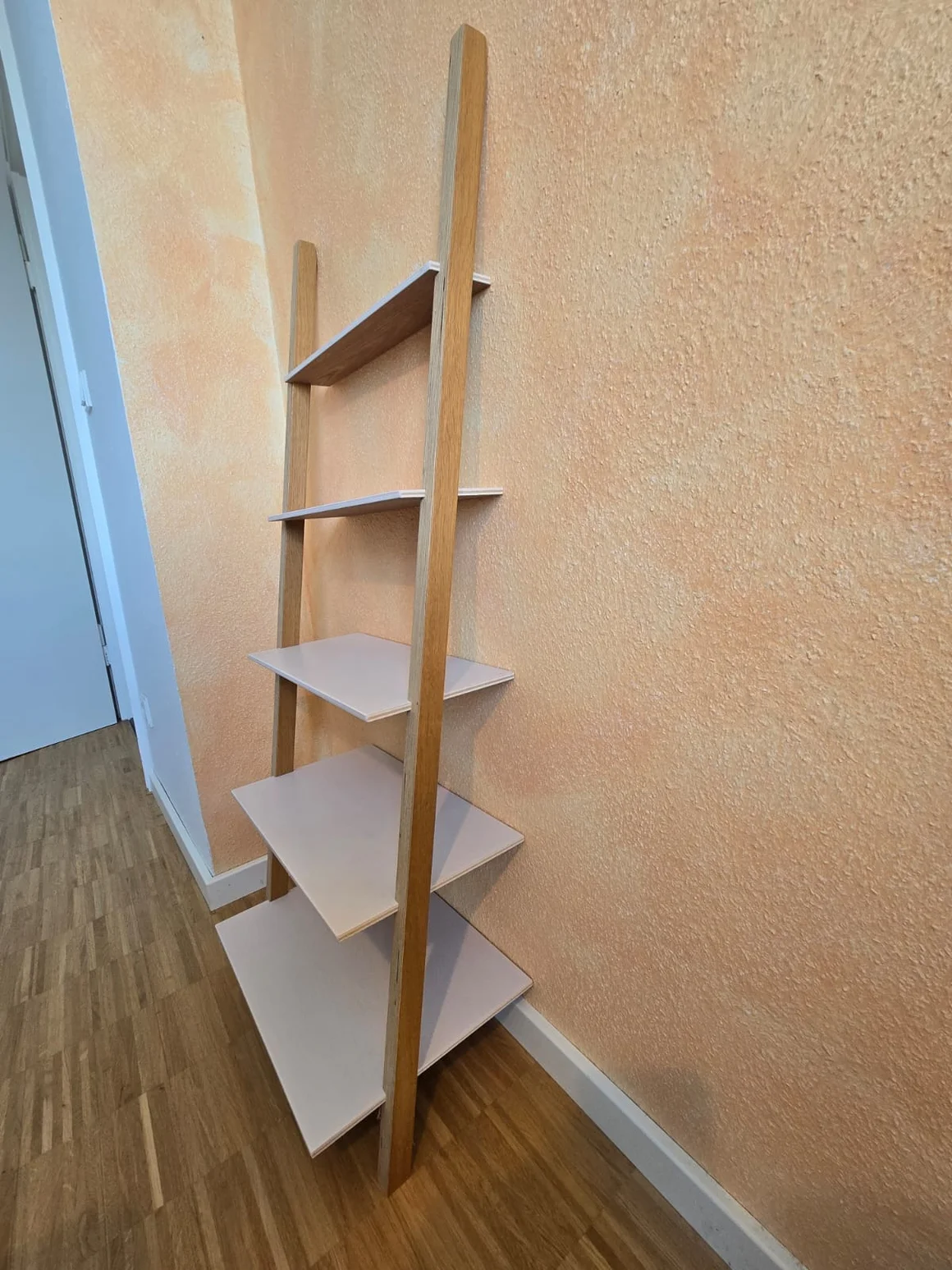 Ein leeres Anlehnregal aus Holz mit weißen Böden.