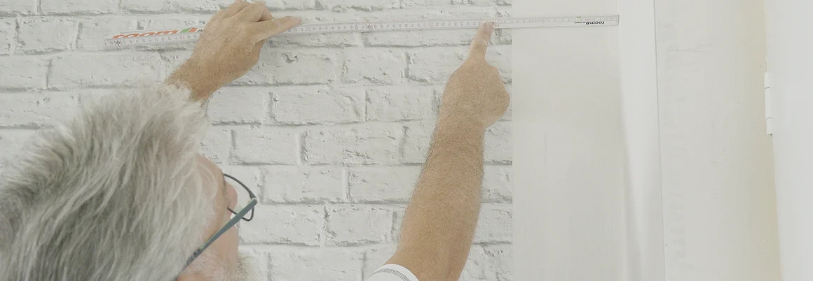 Person misst Wand mit Zollstock ab
