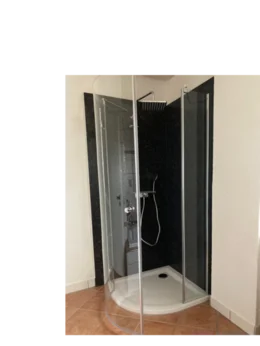 Eine geräumige Duschkabine mit Glaswänden und schwarzer Rückwand.