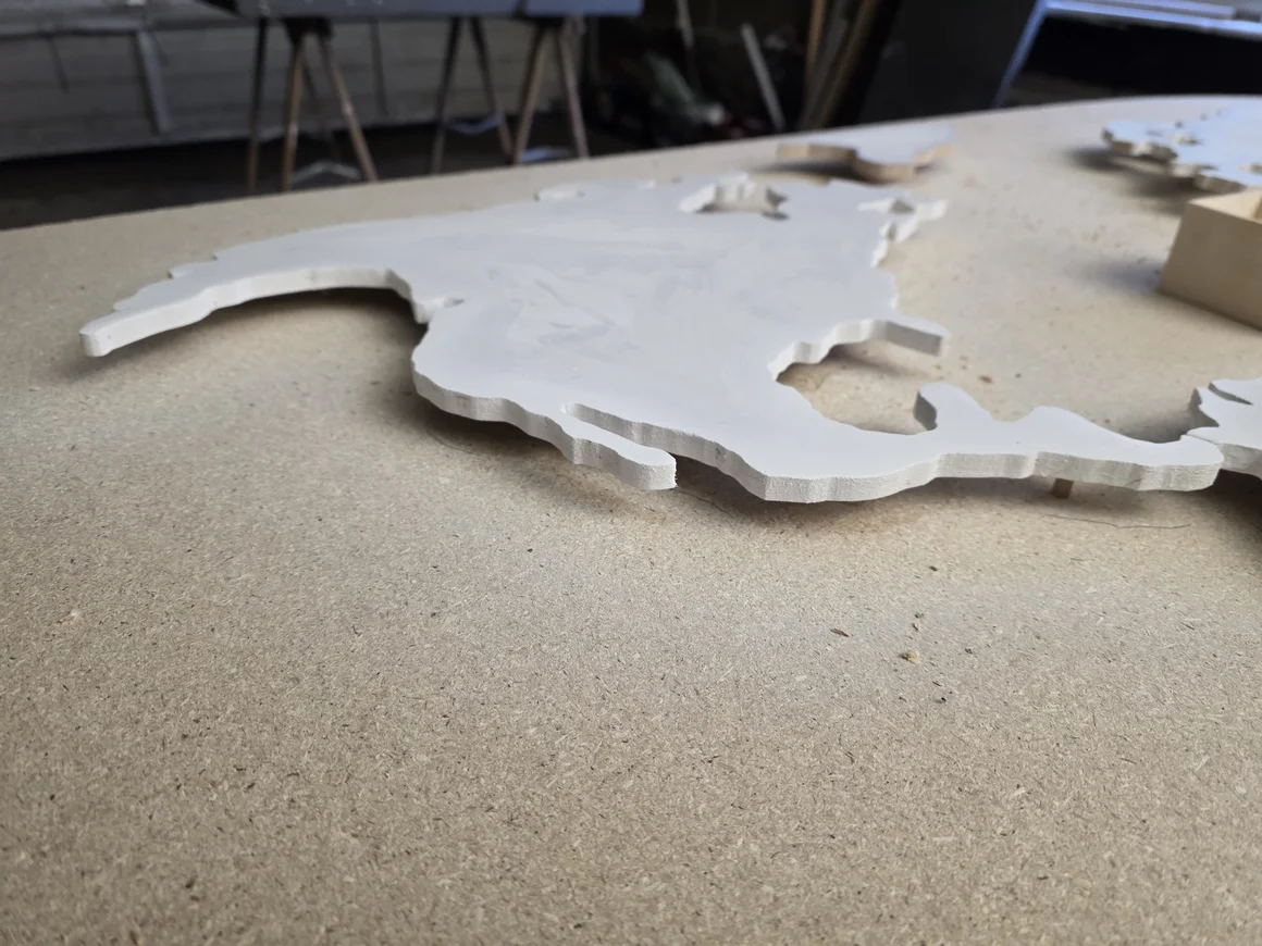 Weiß lackierter Holzausschnitt von Nordamerika auf einer Werkbank.