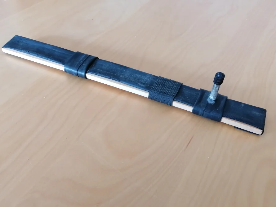 Ein Fahrradreifen ist um ein Holzbrett gewickelt.