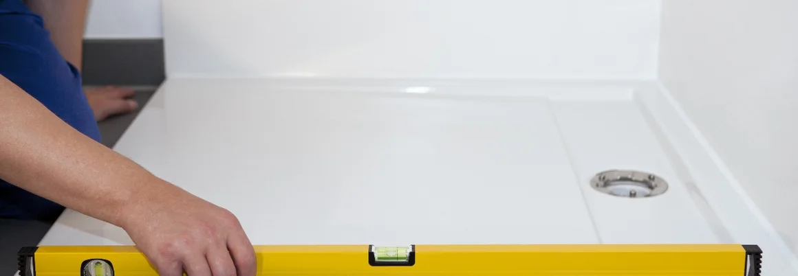 Person prüft Duschwanne mit Wasserwaage