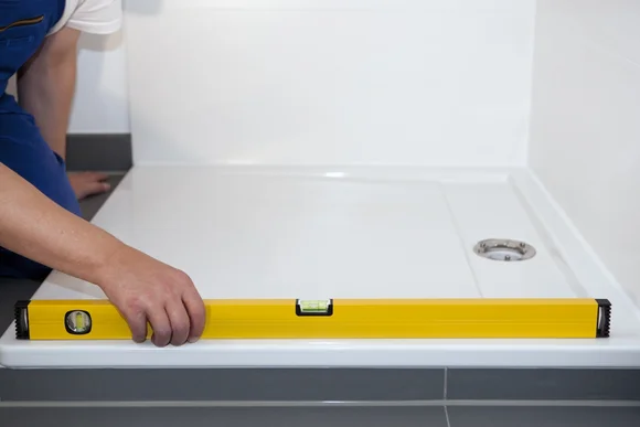 Person prüft Duschwanne mit Wasserwaage