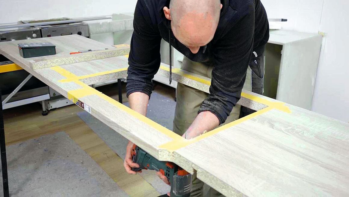 Ein Handwerker beim Arbeitsplatte aussägen.
