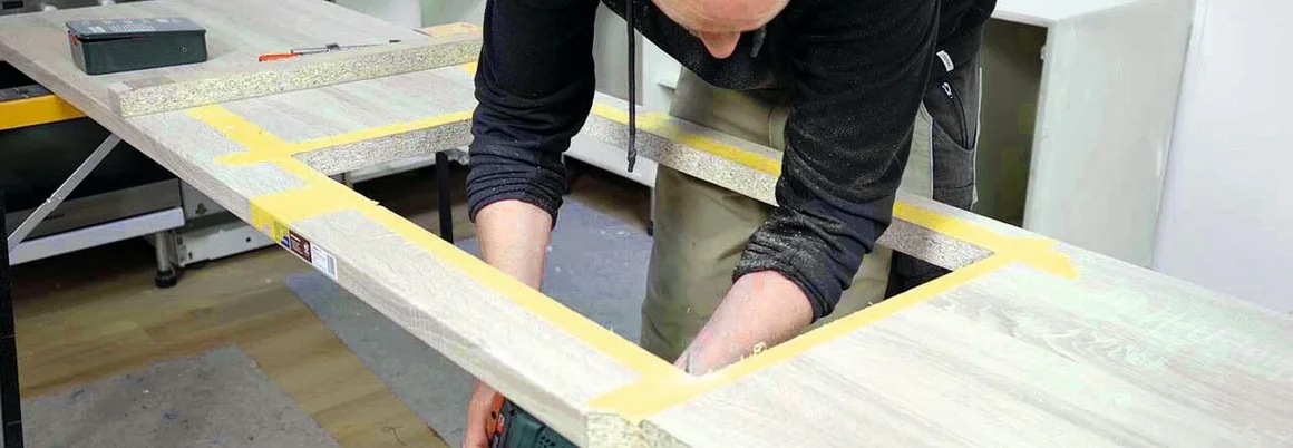 Person sägt Loch in Holzplatte