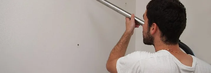 Person saugt Wand mit Staubsauger ab
