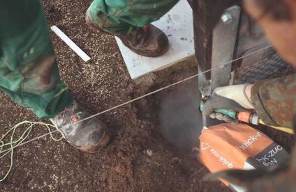 Pfosten betonieren Ein Handwerker betoniert einen Zaunpfosten mit Schnellbeton.