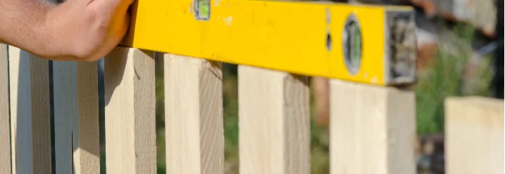 Person baut einen Holzzaun