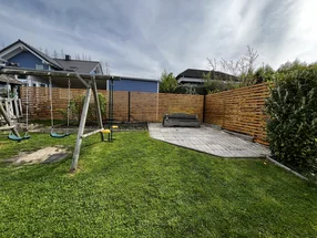 Ein Garten mit einem Schaukelgerüst, einer Bank und einem Holzzaun.