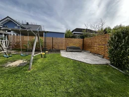 Ein Garten mit einem Schaukelgerüst, einer Bank und einem Holzzaun.