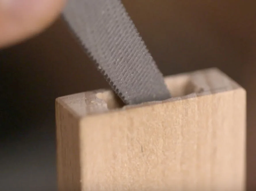 Feile glättet Kante an Holzstück