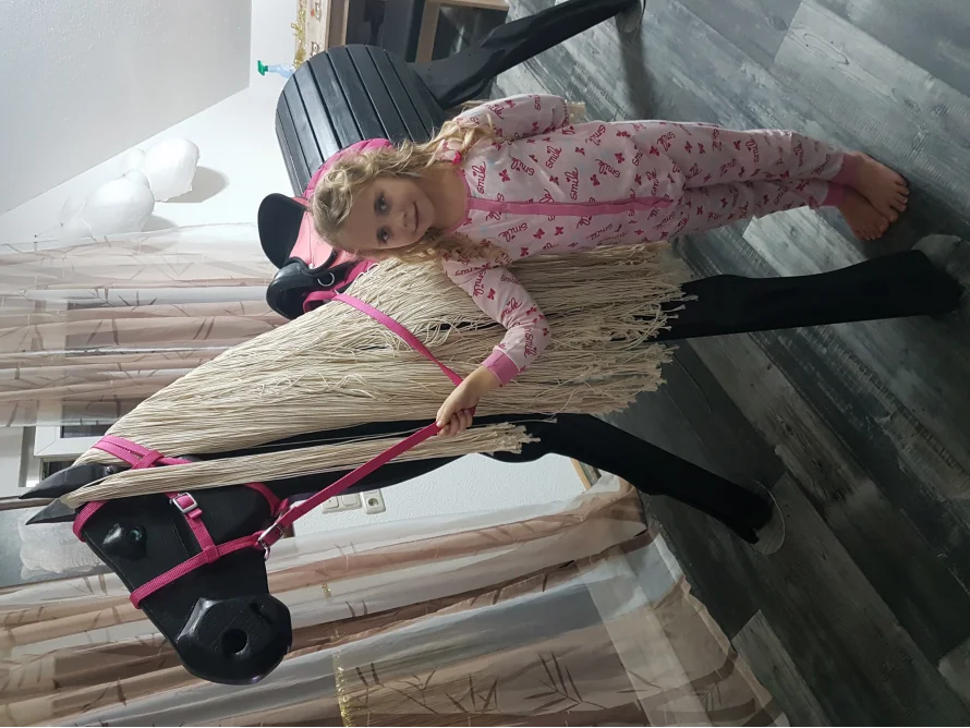 Kind in Schlafanzug neben Spielzeugpferd