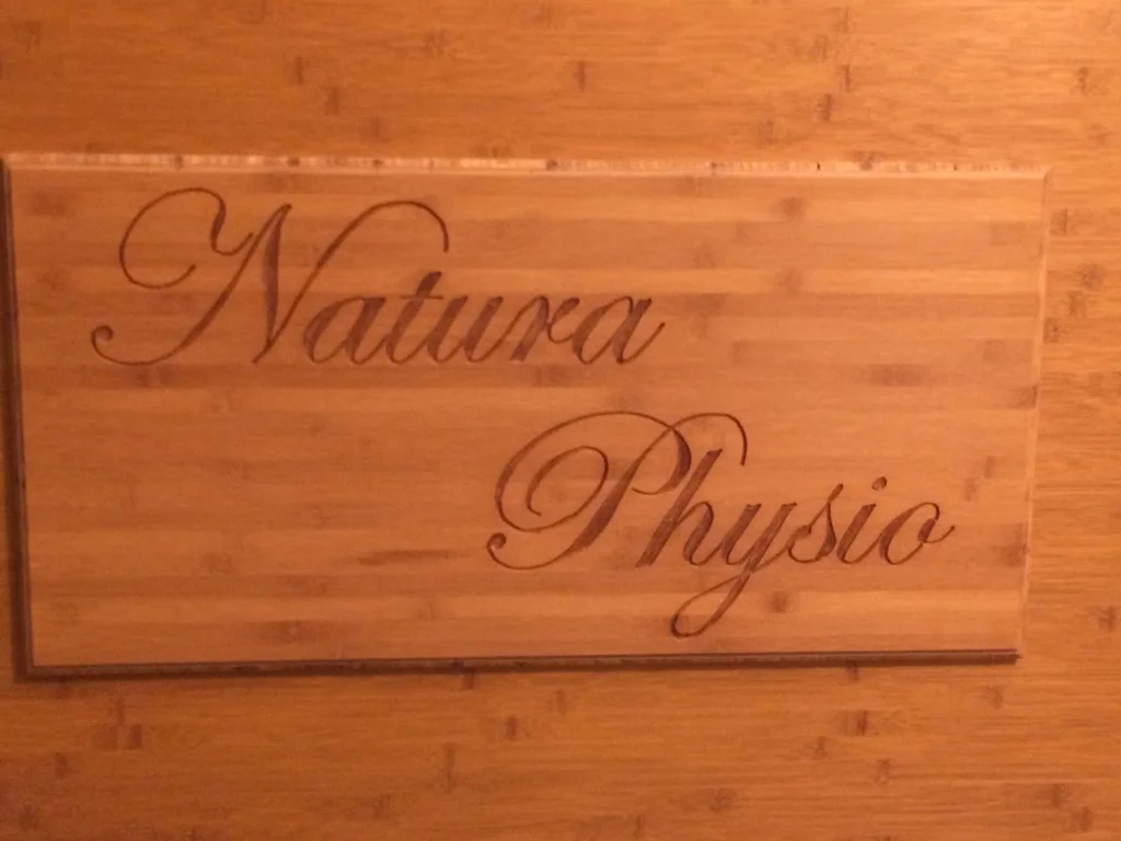 Ein Holzschild mit der Gravur "Natura Physio".