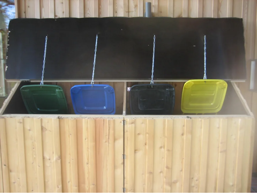 Vier Mülleimer in einem Mülltonnenhäuschen