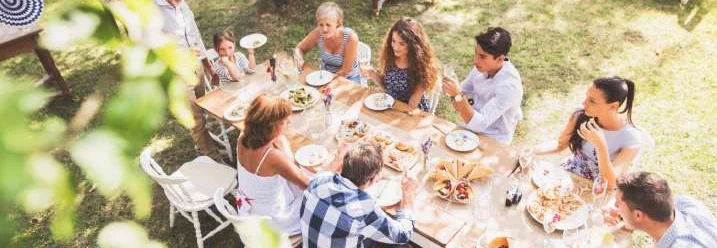 Eine Familie feiert eine Gartenparty an einem langen Tisch.