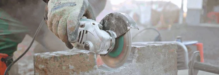 Person schneidet Stein mit Trennschleifer