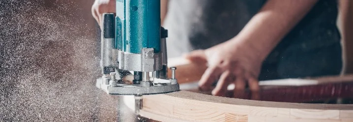 Person fräst Holz mit Oberfräse