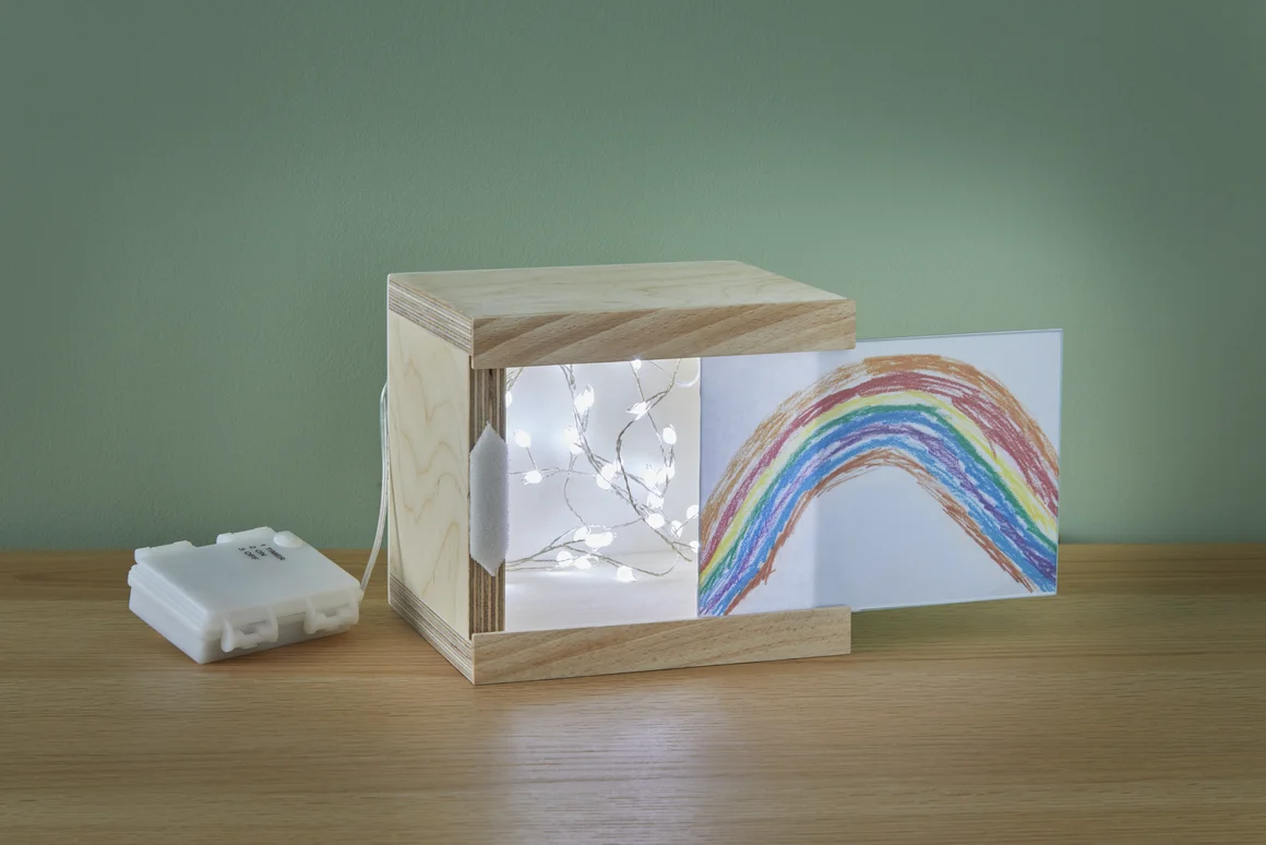 Holzkasten mit Lichterkette und Kinderzeichnung