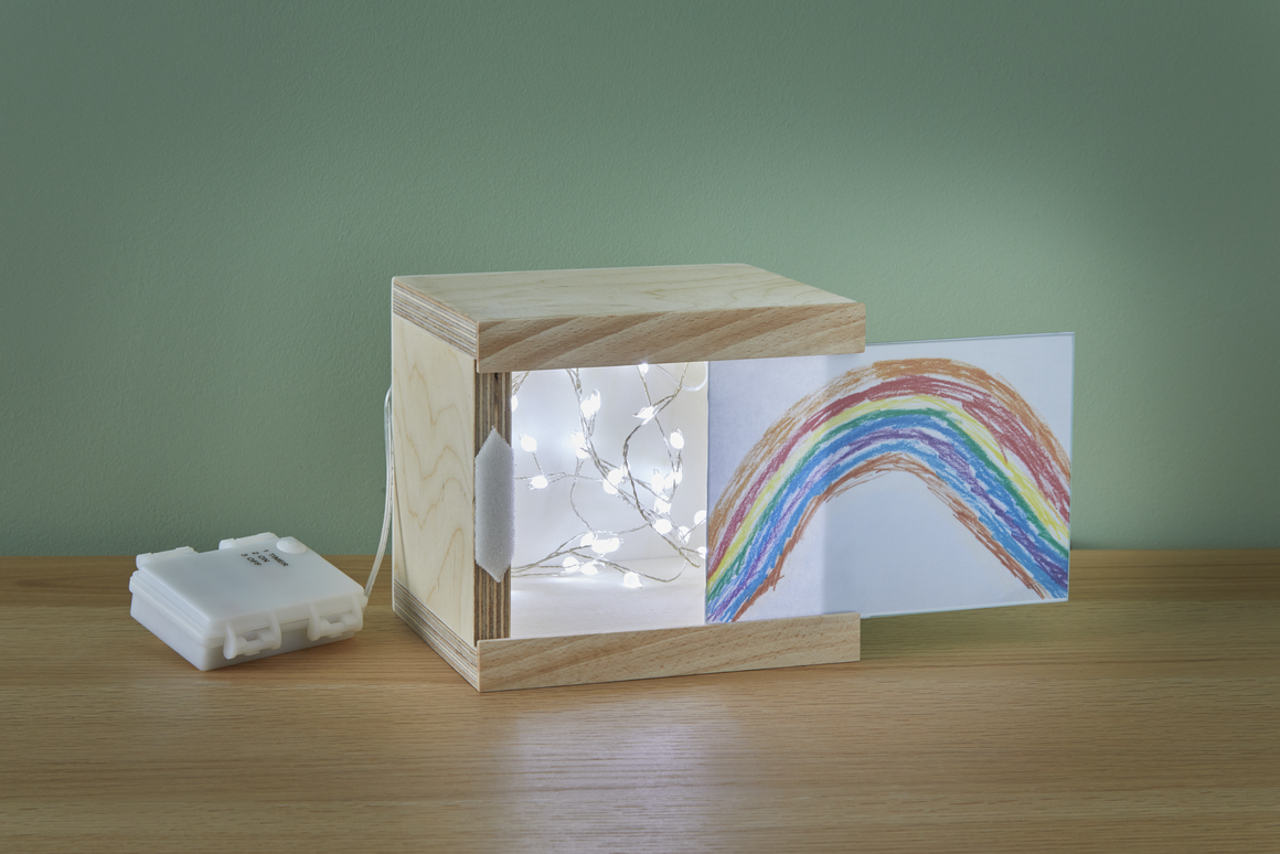 Holzkasten mit Lichterkette und Kinderzeichnung