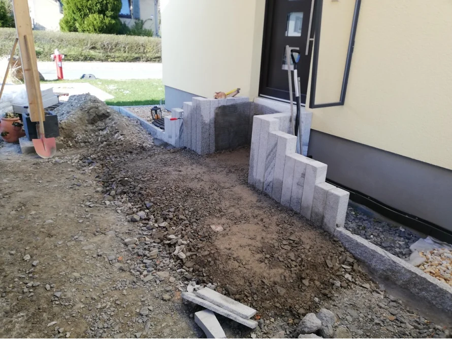 Pflasterarbeiten mit Granitsteinen und Schaufel