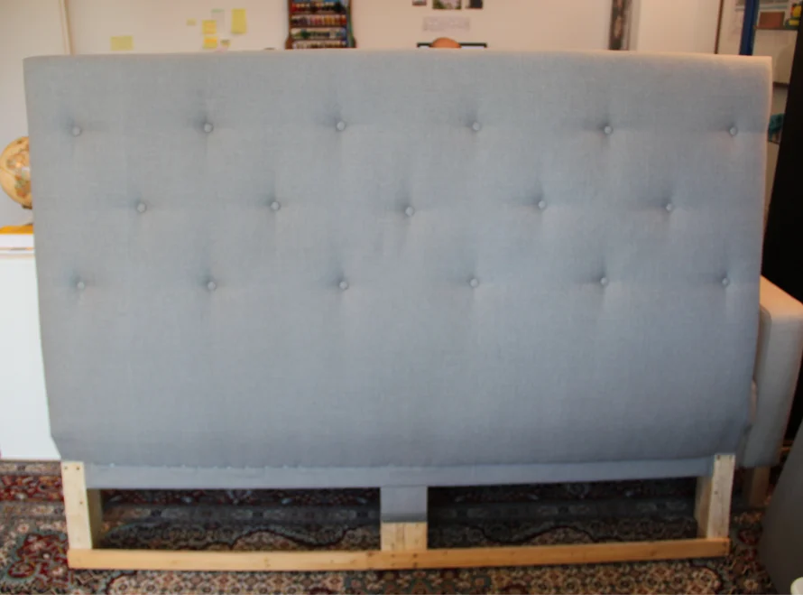 Gepolstertes graues Kopfteil mit Knöpfen