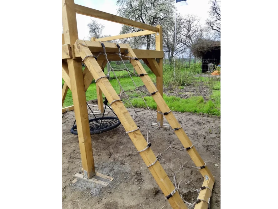 Ein Spielturm aus Holz mit Kletternetz und Nestschaukel.