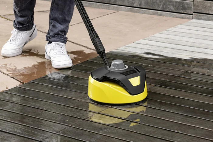 Person reinigt Holzterrasse mit Flächenreiniger