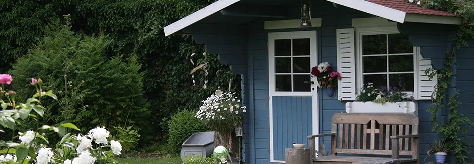 Blaues Gartenhaus mit weißen Fenstern und Tür