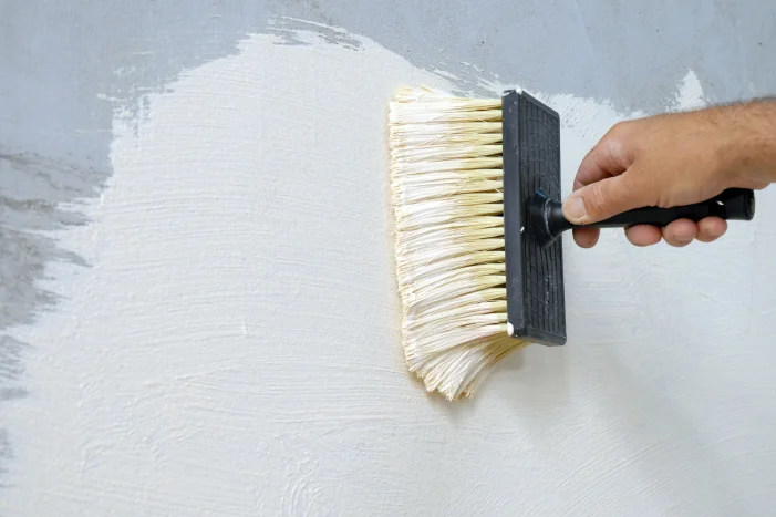 Hand trägt Farbe mit Pinsel auf