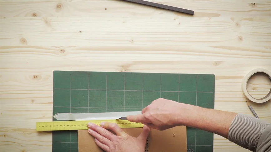 Person schneidet Pappe mit Cuttermesser