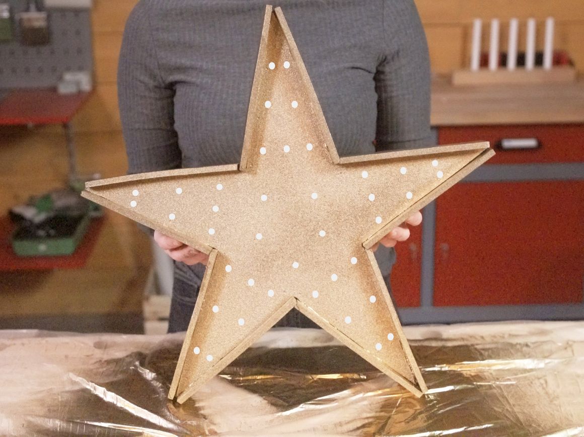 Person hält Holzsstern mit Lichtern