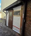 Eine mit Folie verkleidete Tür und Wand, daneben eine Leiter.