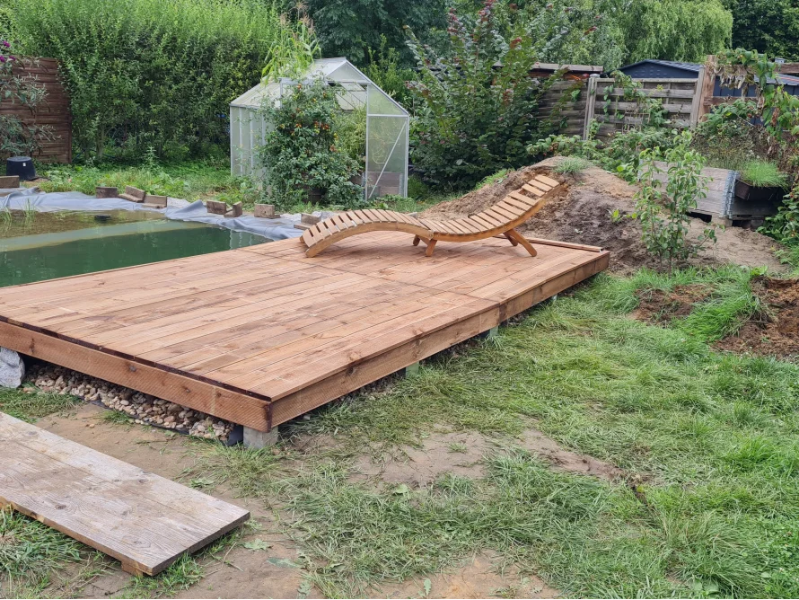 Holzterrasse am Gartenteich mit Liege