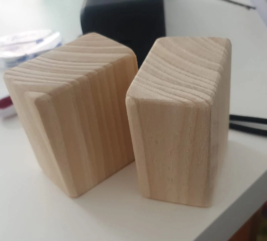 Zwei quaderförmige Möbelfüße aus hellem Holz mit sichtbarer Maserung.