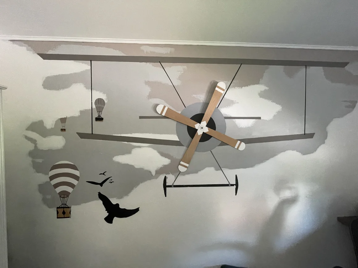Wanddekoration mit einem Flugzeug, Heißluftballons und Vögeln.