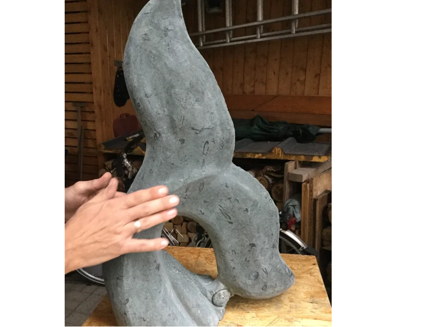 Eine Person berührt eine abstrakte Steinskulptur