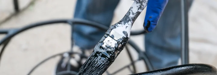 Hand mit Pinsel streicht Metall schwarz