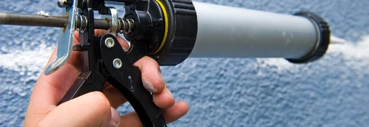 Hand trägt Dichtmittel mit Kartuschenpistole auf