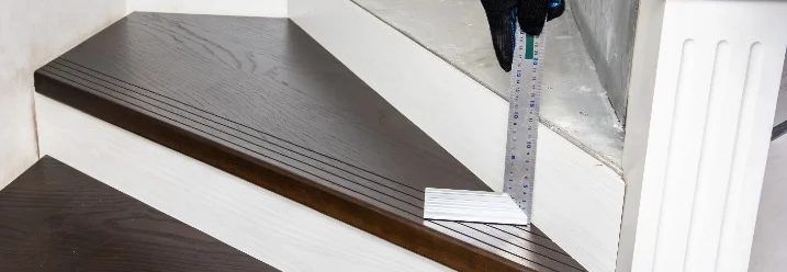 Person misst Holztreppe mit Winkel