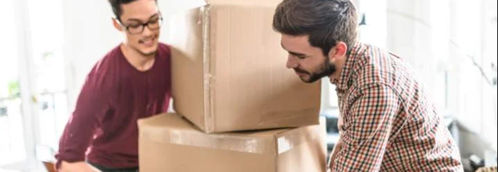 Zwei Personen tragen Umzugskartons