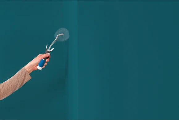 Person streicht Wand mit Farbrolle