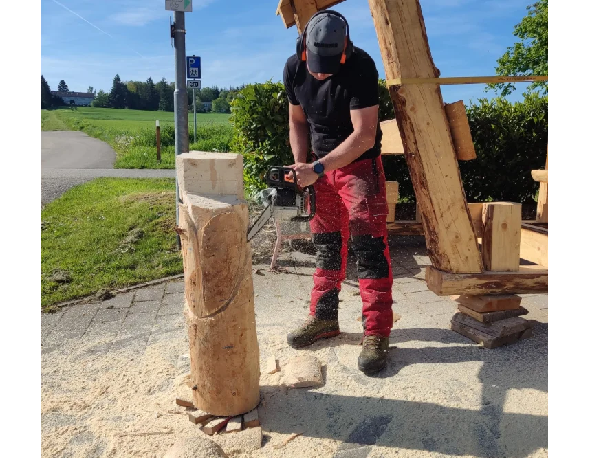 Person bearbeitet Holzstamm mit Kettensäge