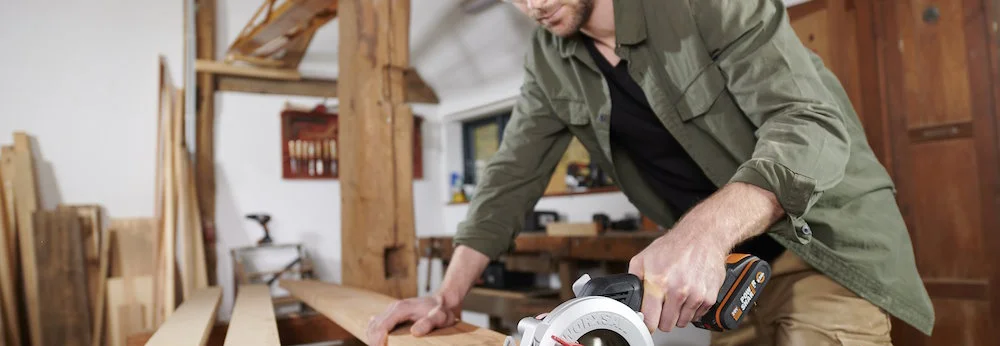 Person sägt Holz mit Kreissäge