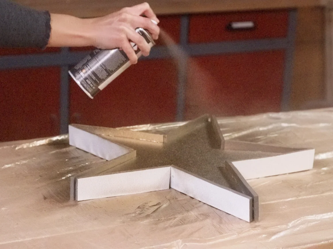 Person sprüht einen Stern mit goldener Farbe an