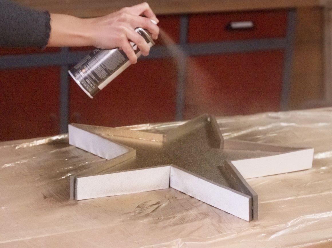 Person sprüht einen Stern mit goldener Farbe an