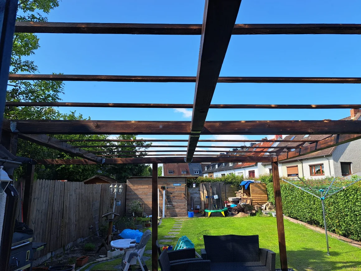 Das Grundgerüst einer Holzpergola in einem Garten.