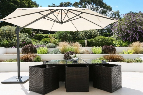 Gartenmöbel aus Rattan mit großem Sonnenschirm auf einer Terrasse.