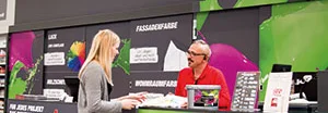 toom Baumarkt Mitarbeiterin berät eine Kundin am Farbmischservice.