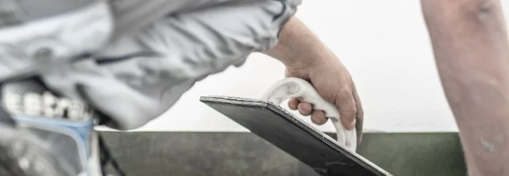 Person verfutigt Fliesen mit Kelle