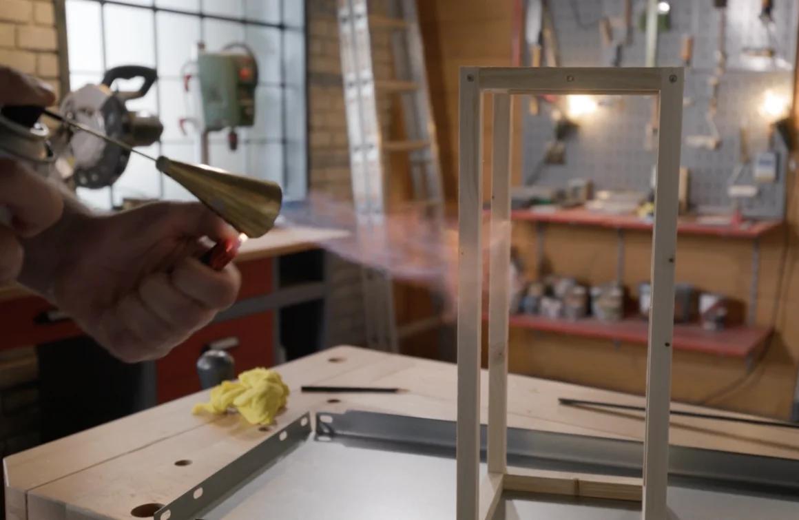 Person bearbeitet Holzrahmen mit Gasbrenner